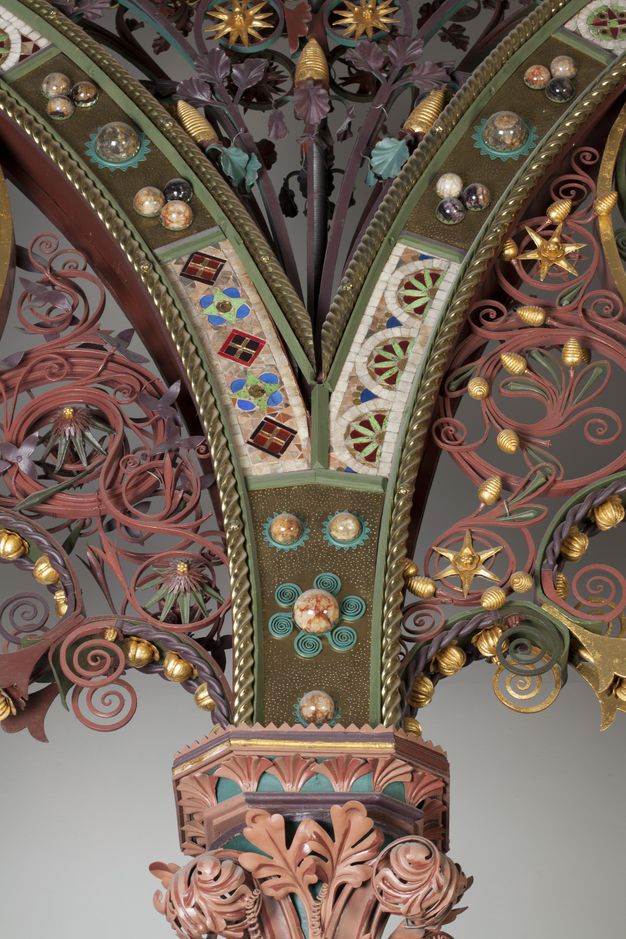 Choir screen. Detail view of where two arches spring from a shared capital. Metalwork, like paper quilling, painted gold, glass, stone, and enamelled patterns create a jewelled effect.