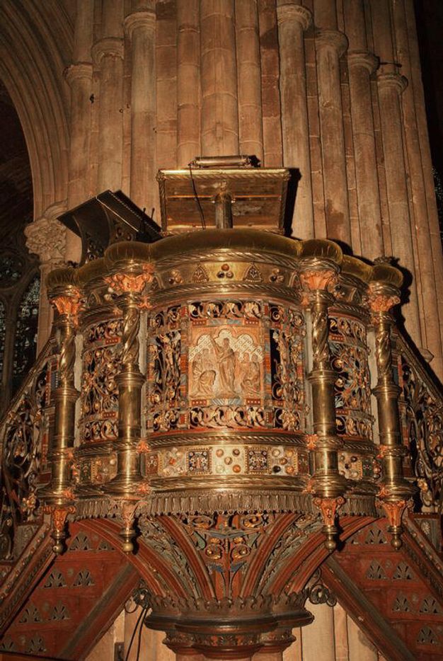 Pulpit. A lectern against a clustered column is accessed by stairs to each side. It curves away from the column like a tiny balcony. Every surface is gilded, painted, or appears bejewelled.