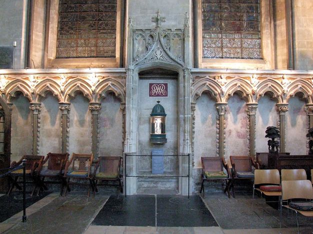Choir screen. Colour photograph of a stone structure set against a stone wall so the tri-lobed arches appear filled in. The columns are lined with flame-like ornaments.